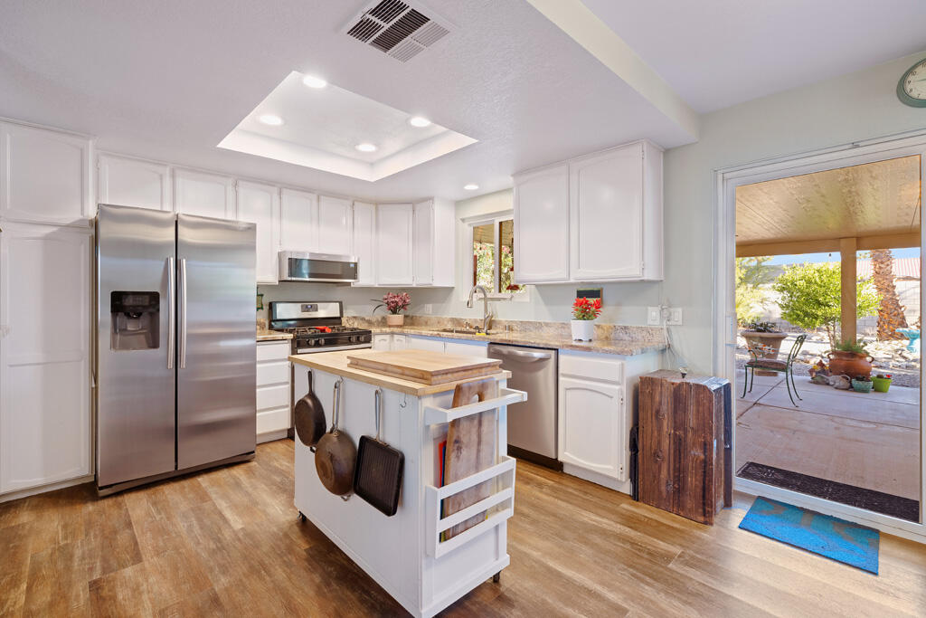 68110 Risueno Road Cathedral City, CA 92234 - Photo 4 of 33 a kitchen with a refrigerator a sink dishwasher a stove a refrigerator and a dining table with wooden floor