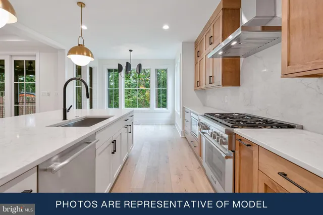 a large kitchen with stainless steel appliances granite countertop a stove a sink dishwasher and white cabinets with wooden floor