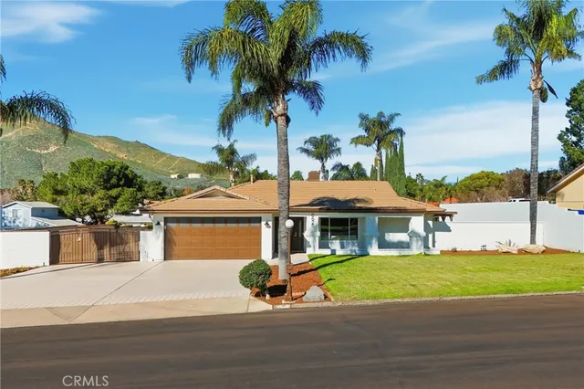 a view of a white house with a large pool and a yard with palm trees