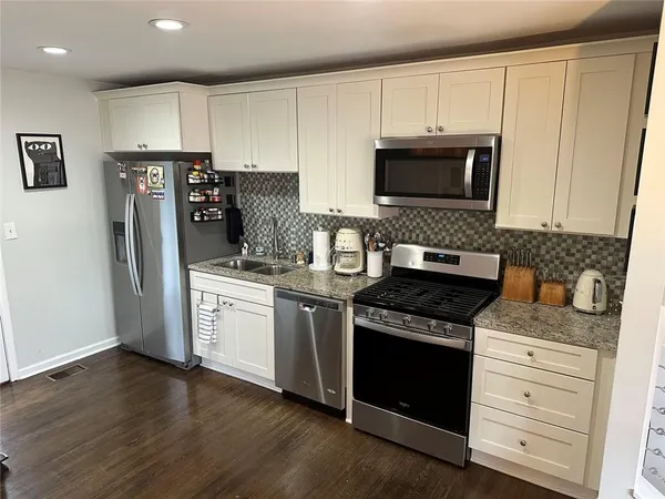 a kitchen with granite countertop white cabinets and stainless steel appliances