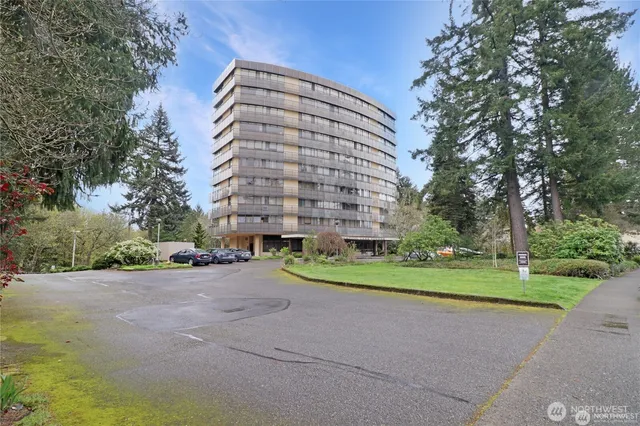 a view of a road with a building and trees in the background