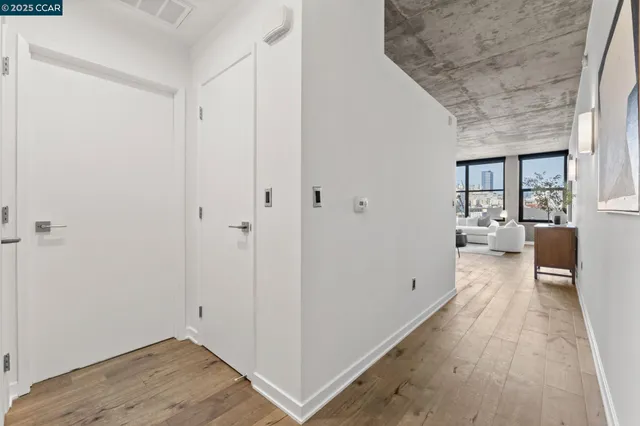 a view of a hallway with wooden floor and a bathroom
