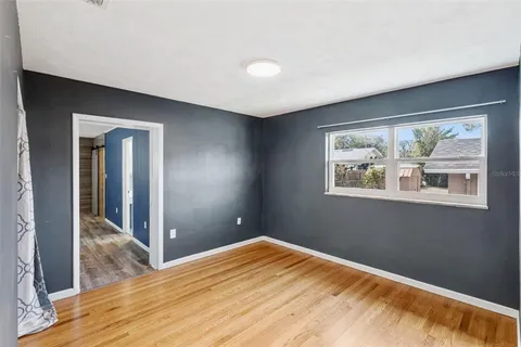 a view of an empty room with window and wooden floor