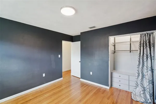 a view of an empty room with window and wooden floor