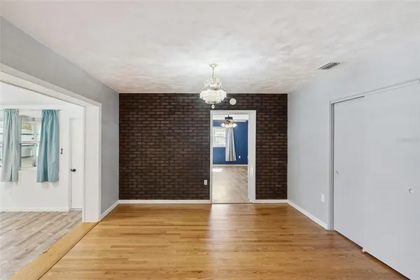 a view of empty room with wooden floor and kitchen