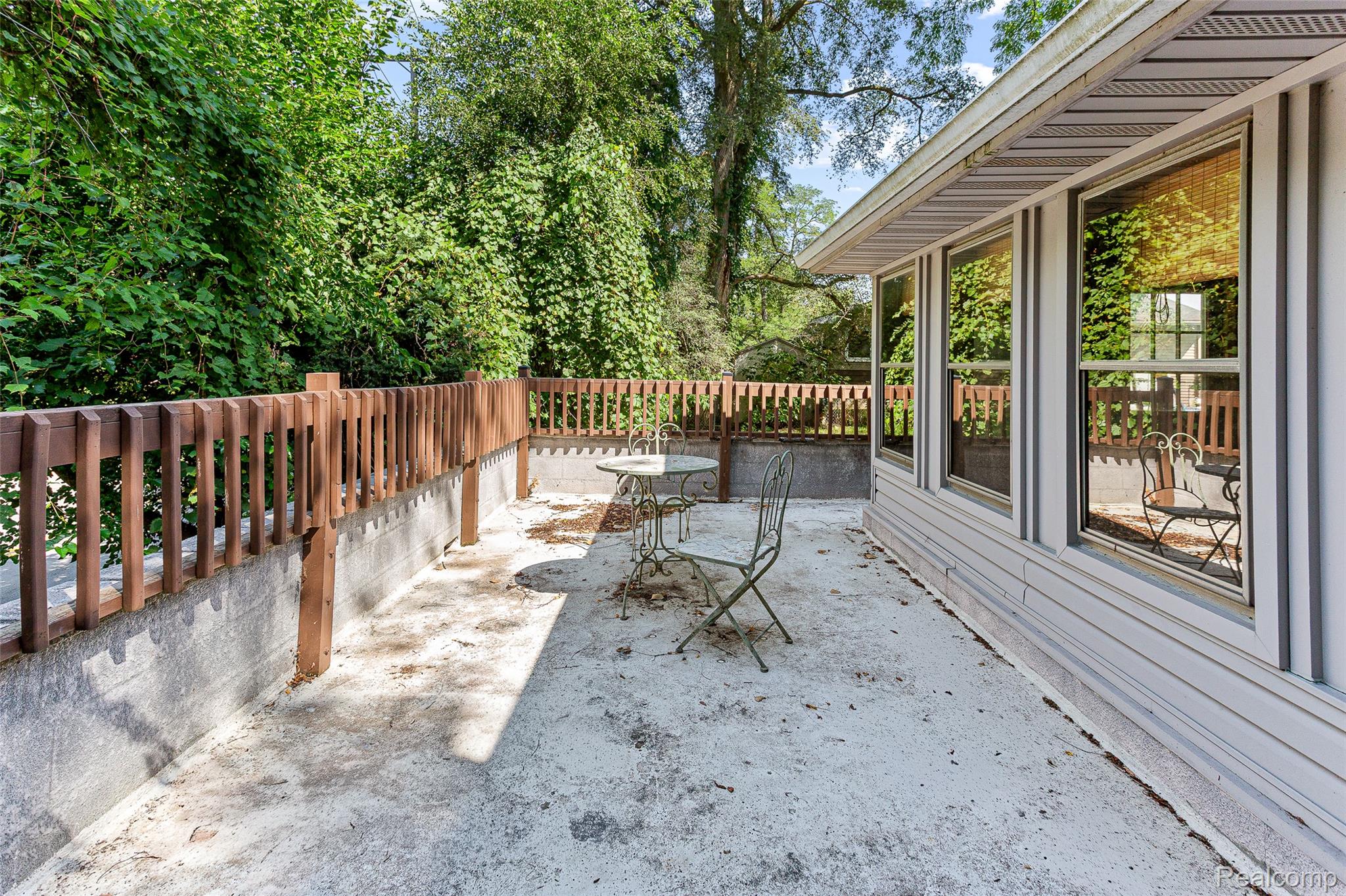 2550 Loon Lake Road Wixom, MI 48393 - Photo 5 of 36 Concrete patio area with a wood-finish railing and mature perimeter landscaping