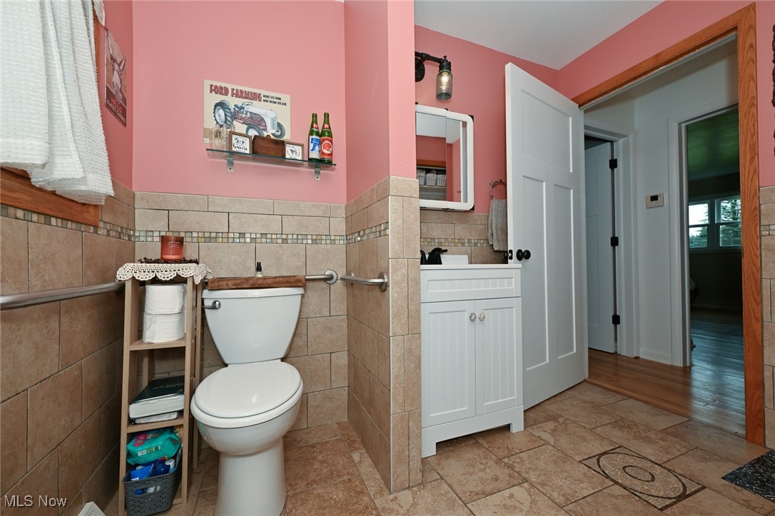 2150 Wise Road Green, OH 44720 - Photo 27 of 50 Bathroom with tile walls, decorative backsplash, tile patterned floors, toilet, and vanity