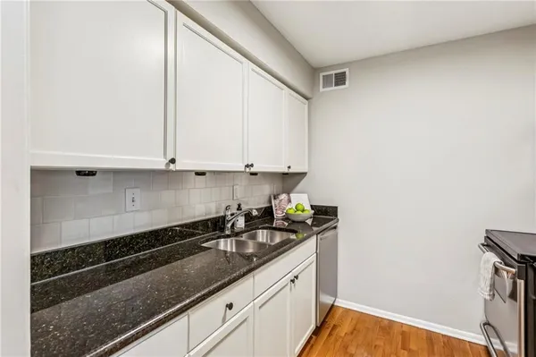 a kitchen with granite countertop white cabinets and black appliances