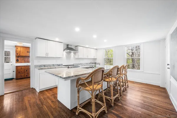 a kitchen with stainless steel appliances granite countertop a stove top oven a sink dishwasher and white cabinets with wooden floor