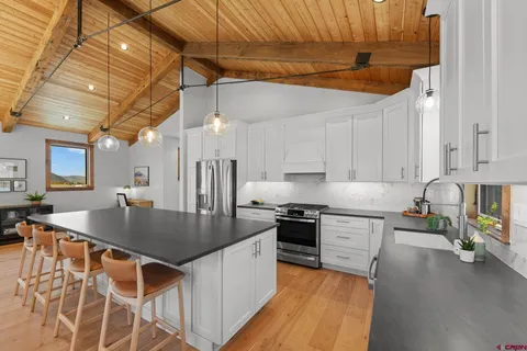 a kitchen with stainless steel appliances granite countertop a sink a stove and a wooden floors