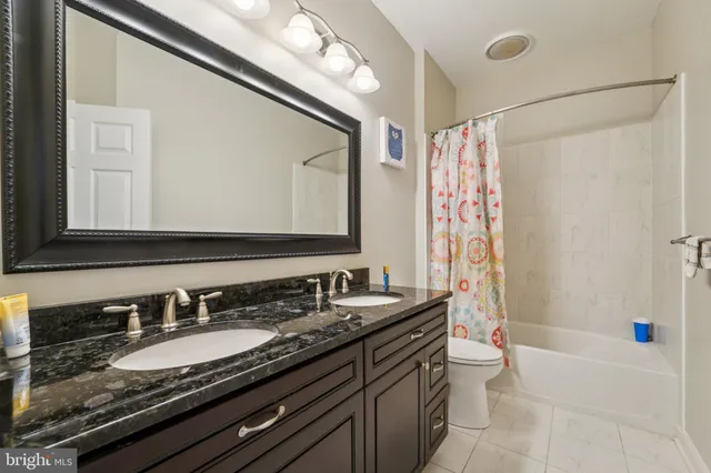 a bathroom with a granite countertop sink a toilet a mirror a vanity a bathtub and shower