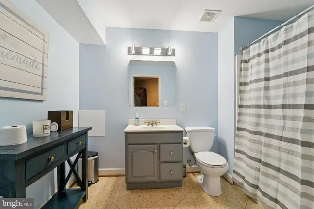 a bathroom with a toilet sink vanity and mirror