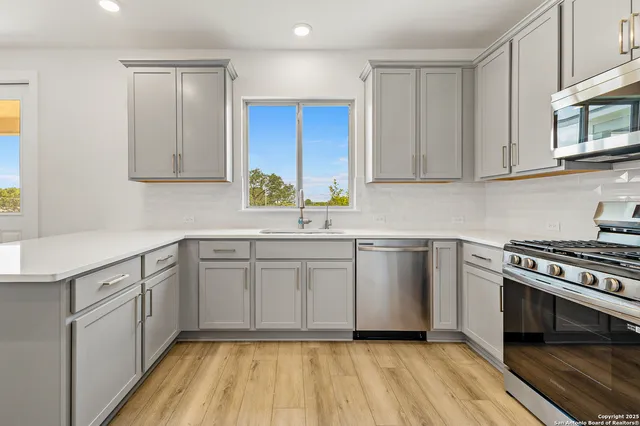a kitchen with stainless steel appliances granite countertop a stove and white cabinets