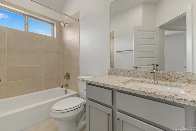 a bathroom with a granite countertop sink toilet mirror and bathtub