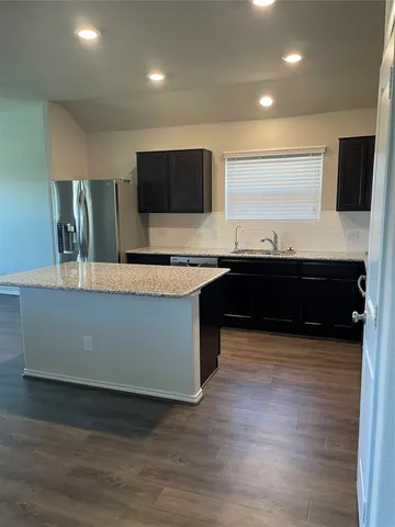 a view of kitchen with stainless steel appliances wooden cabinets and wooden floor