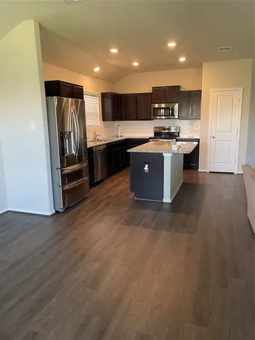 a kitchen with stainless steel appliances kitchen island granite countertop a refrigerator and a stove top oven