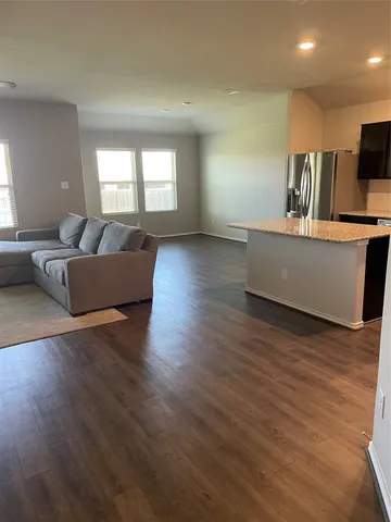 a living room with couches and kitchen view with wooden floor