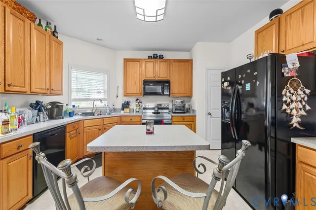 a view of a kitchen with kitchen island granite countertop a sink appliances and cabinets