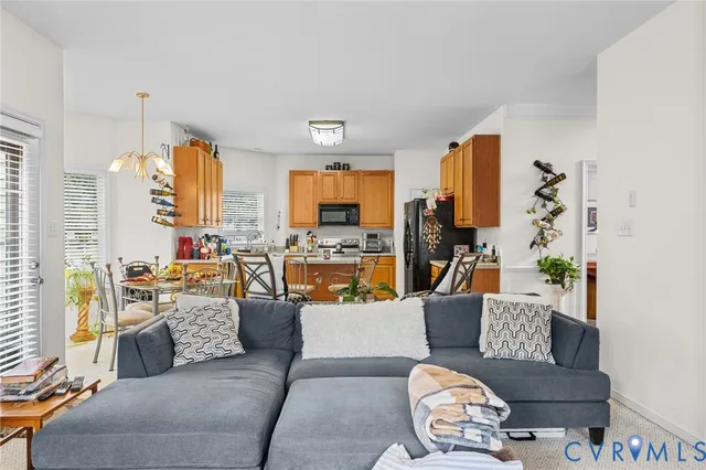 a living room with furniture kitchen view and a chandelier
