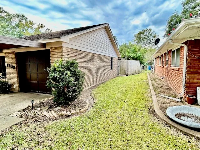 a view of a backyard with plants and brick wall