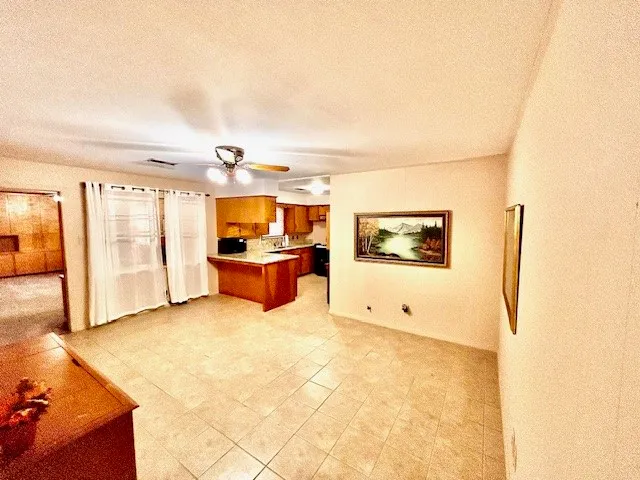 an empty room with a chandelier fan and a large window