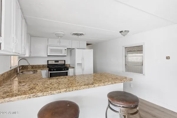 a kitchen with granite countertop white cabinets and white appliances