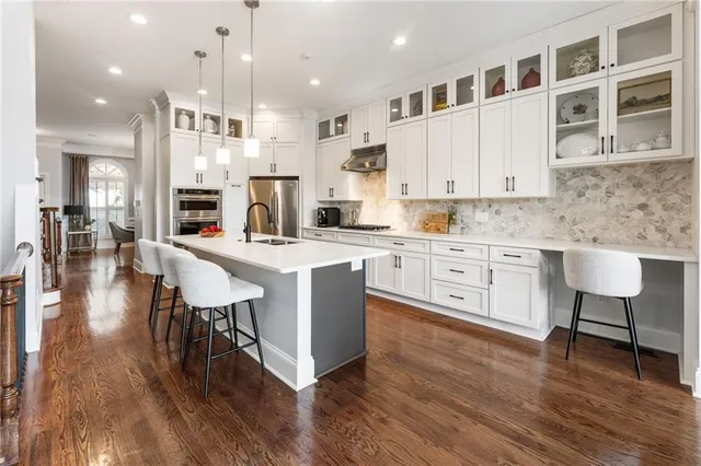 a kitchen with stainless steel appliances kitchen island granite countertop a table chairs sink and cabinets