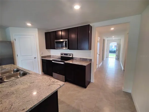 a kitchen with stainless steel appliances kitchen island granite countertop a refrigerator and a sink