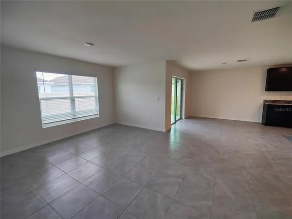 an empty room with windows and flat screen tv