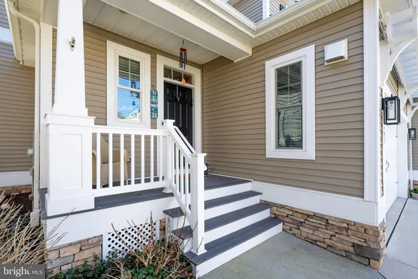 a kitchen with stainless steel appliances kitchen island granite countertop a refrigerator a stove top oven a sink dishwasher and white cabinets with wooden floor