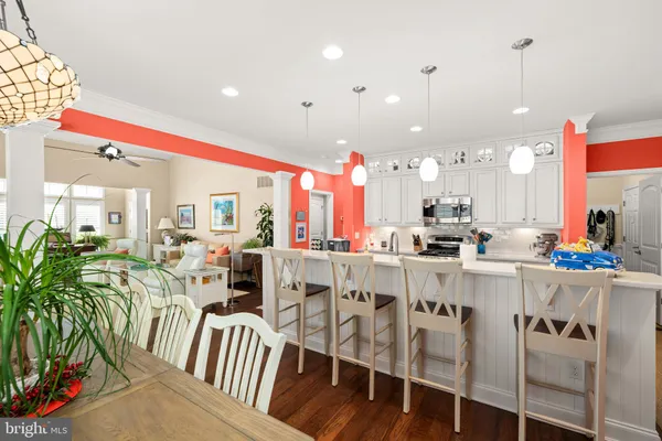 a kitchen with stainless steel appliances kitchen island granite countertop a stove a sink a refrigerator and white cabinets with wooden floor