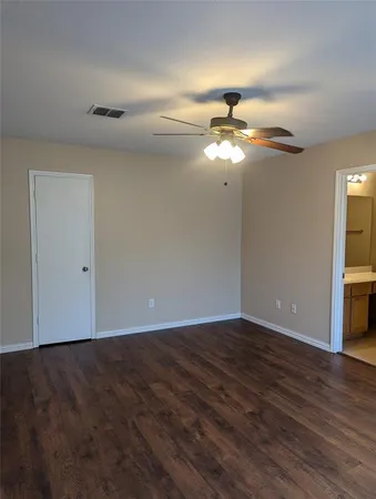 a view of an empty room with chandelier fan and wooden floor