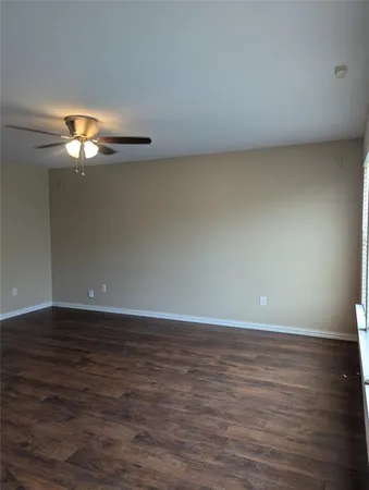 a view of an empty room with chandelier fan and wooden floor