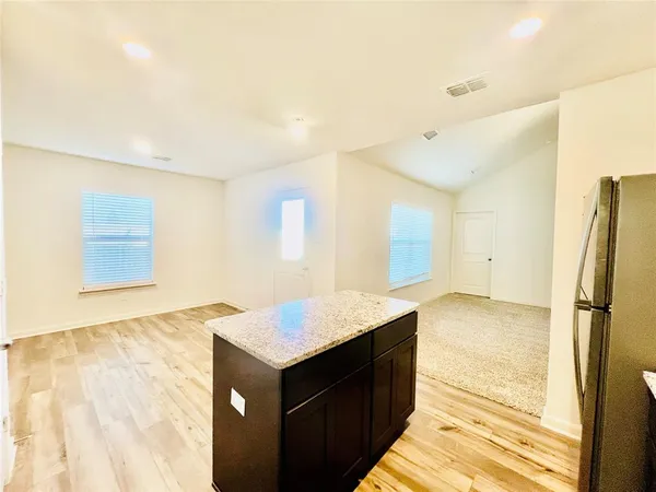 a kitchen with granite countertop a refrigerator and a stove top oven