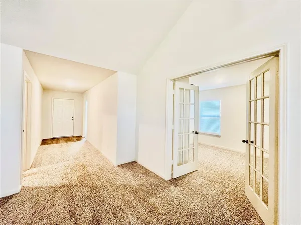 an empty room with a chandelier fan and wooden floor