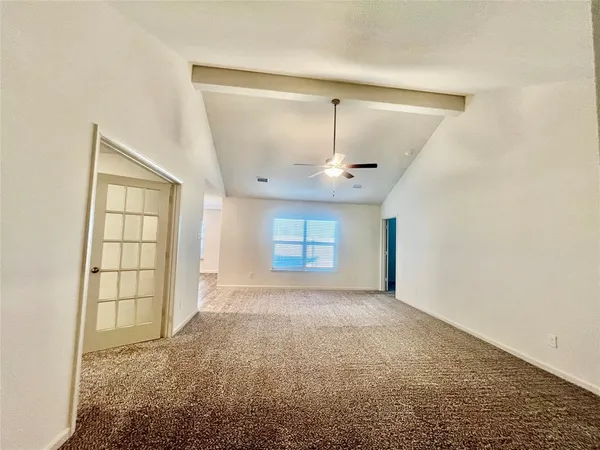 an empty room with windows and chandelier fan