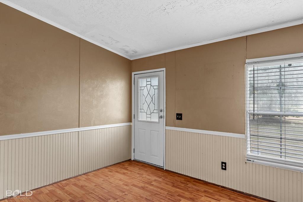 9720 Osburn Road Shreveport, LA 71129 - Photo 2 of 30 Sunroom featuring warm taupe walls with white beadboard wainscoting, wood-finish flooring, and abundant natural light from a multi-pane window