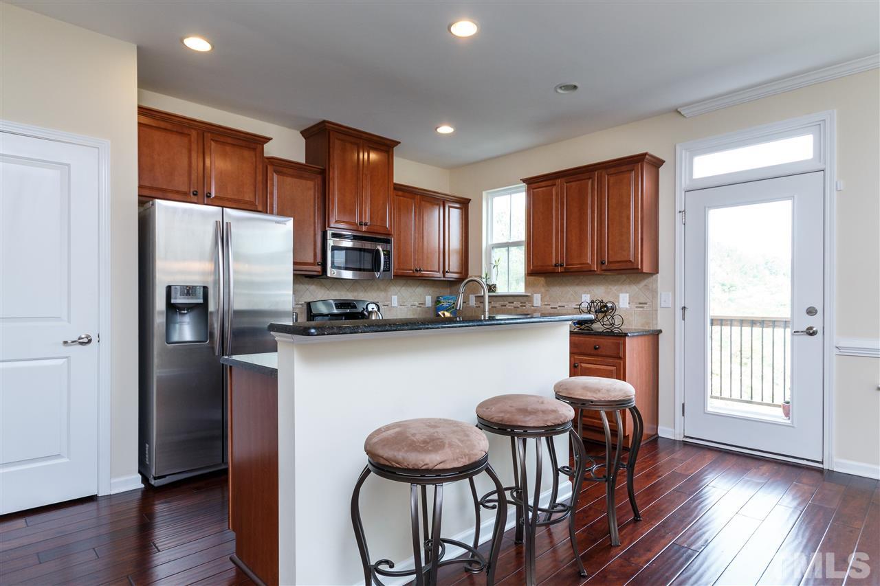 1305 Rodessa Run Raleigh, NC 27607 - Photo 11 of 25 Enjoy this kitchen with stainless steel appliances, granite counter tops, hardwoods, bar, pantry, and plenty of cabinet space! Perfect area for entertaining with the balcony just off of the kitchen.