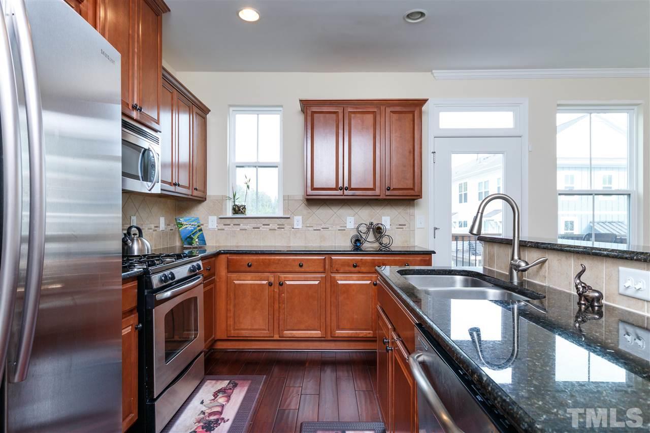 1305 Rodessa Run Raleigh, NC 27607 - Photo 12 of 25 Enjoy this kitchen with stainless steel appliances, granite counter tops, hardwoods, bar, pantry, and plenty of cabinet space! Perfect area for entertaining with the balcony just off of the kitchen.