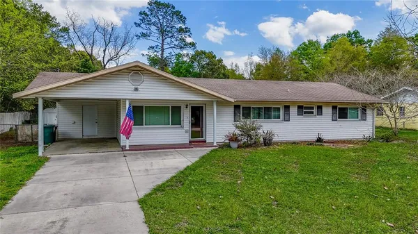 a view of a house with a yard plants and large tree