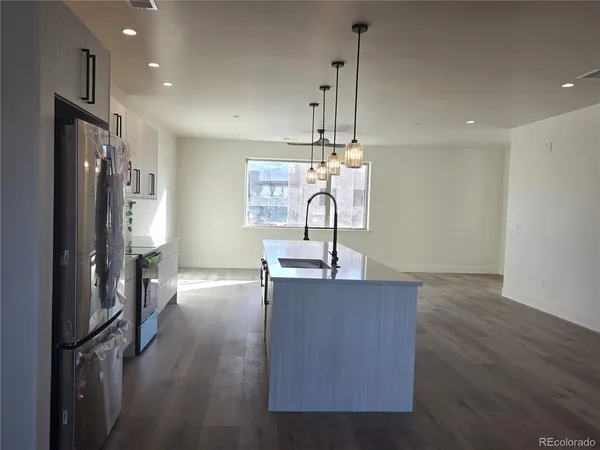 a large kitchen with stainless steel appliances a large counter top a stove and a wooden floors