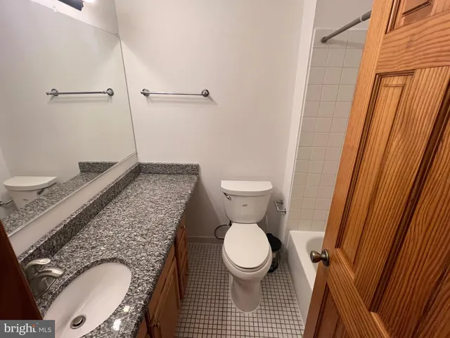 a bathroom with a granite countertop toilet and a sink