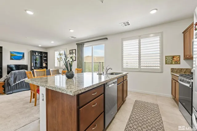 a large kitchen with granite countertop a stove a sink a dining table and chairs