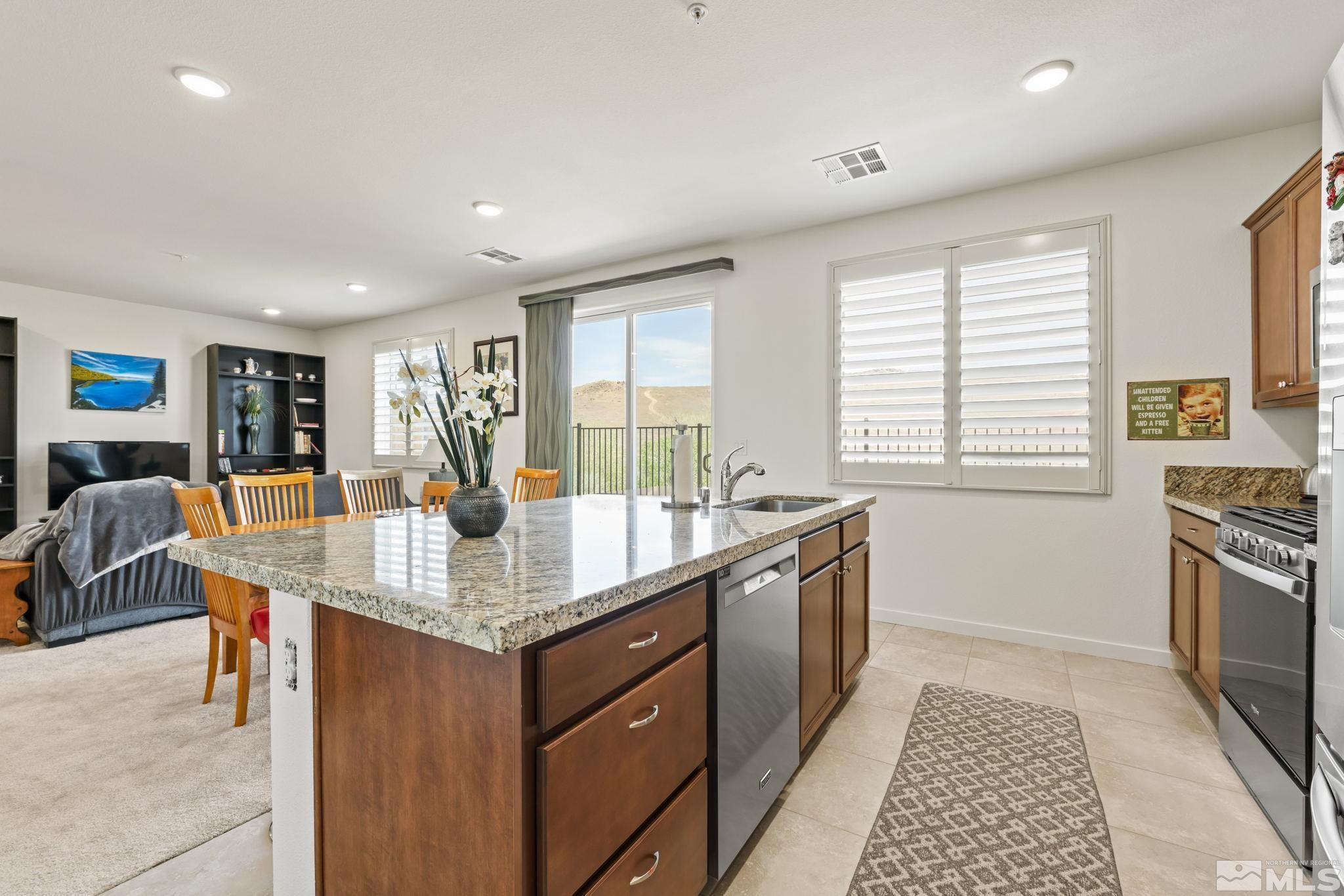 4928 Black Falcon Way Sun Valley, NV 89433 - Photo 2 of 32 a large kitchen with granite countertop a stove a sink a dining table and chairs