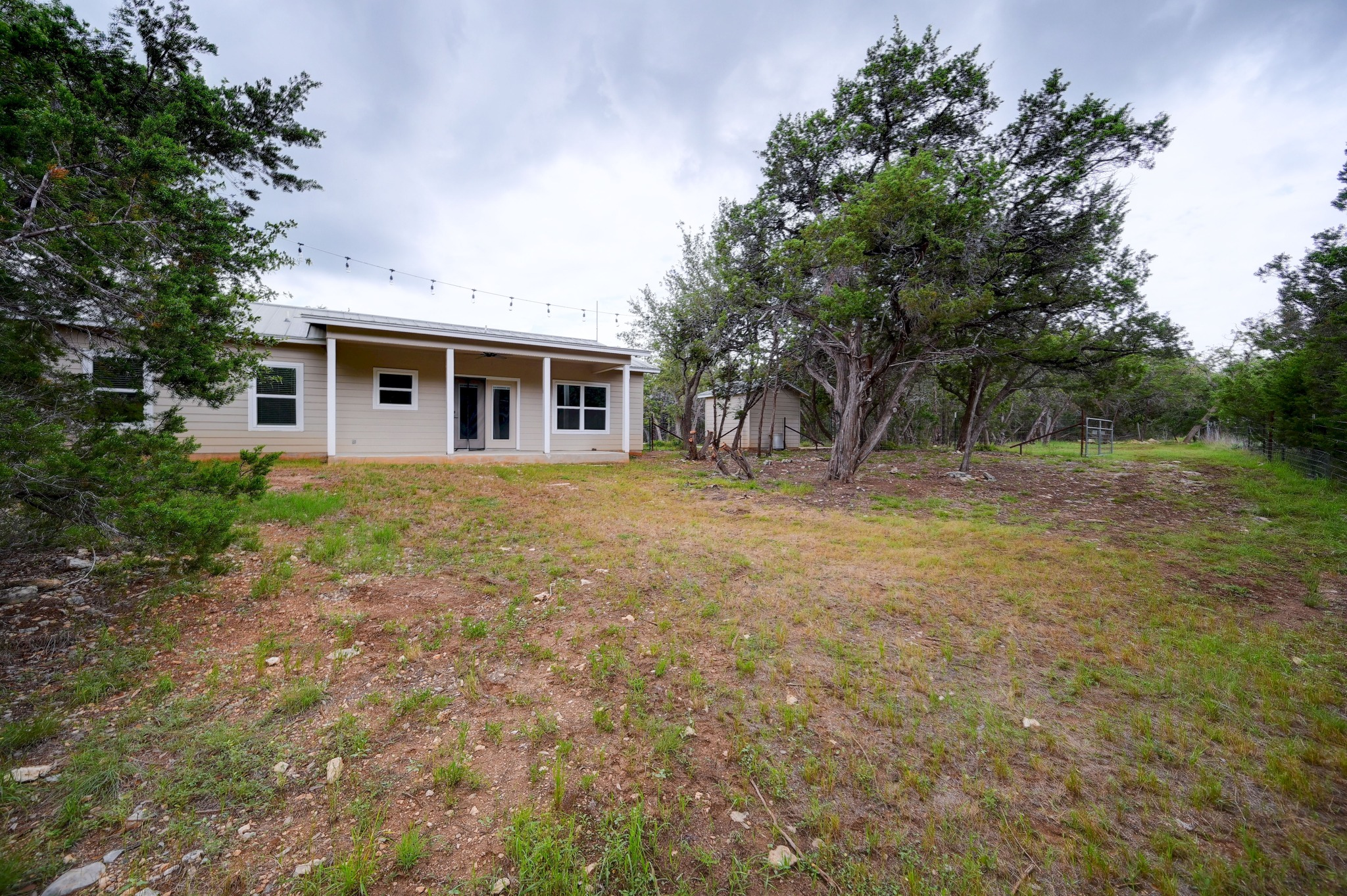 231 North Rainbow Ranch Road Wimberley, TX 78676 - Photo 28 of 40 A tranquil retreat, this single-story home features a welcoming covered patio overlooking a natural, treed landscape.