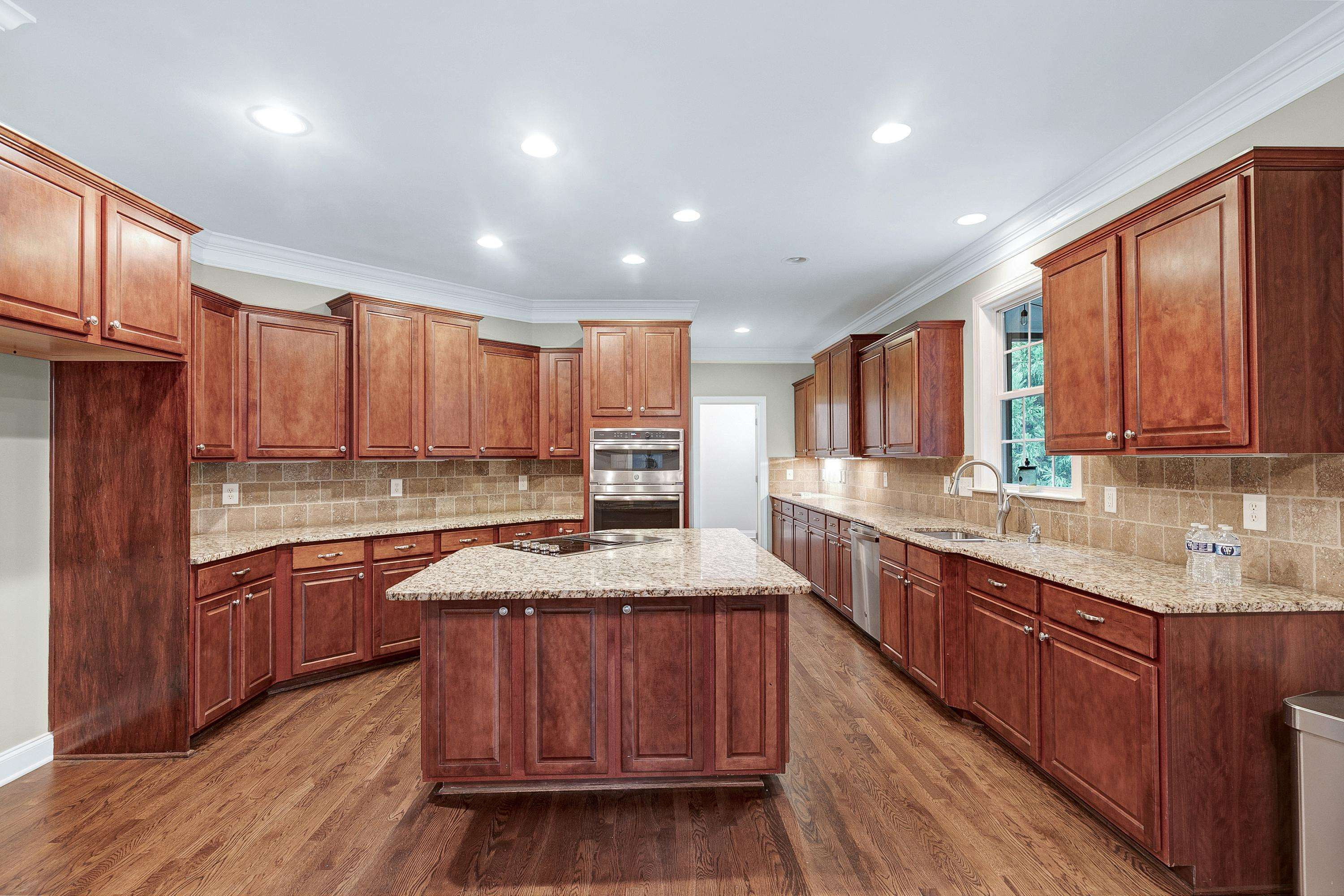 8431 Henderson Road Apex, NC 27539 - Photo 15 of 56 a kitchen with stainless steel appliances granite countertop wooden cabinets a sink and dishwasher a refrigerator with wooden floor