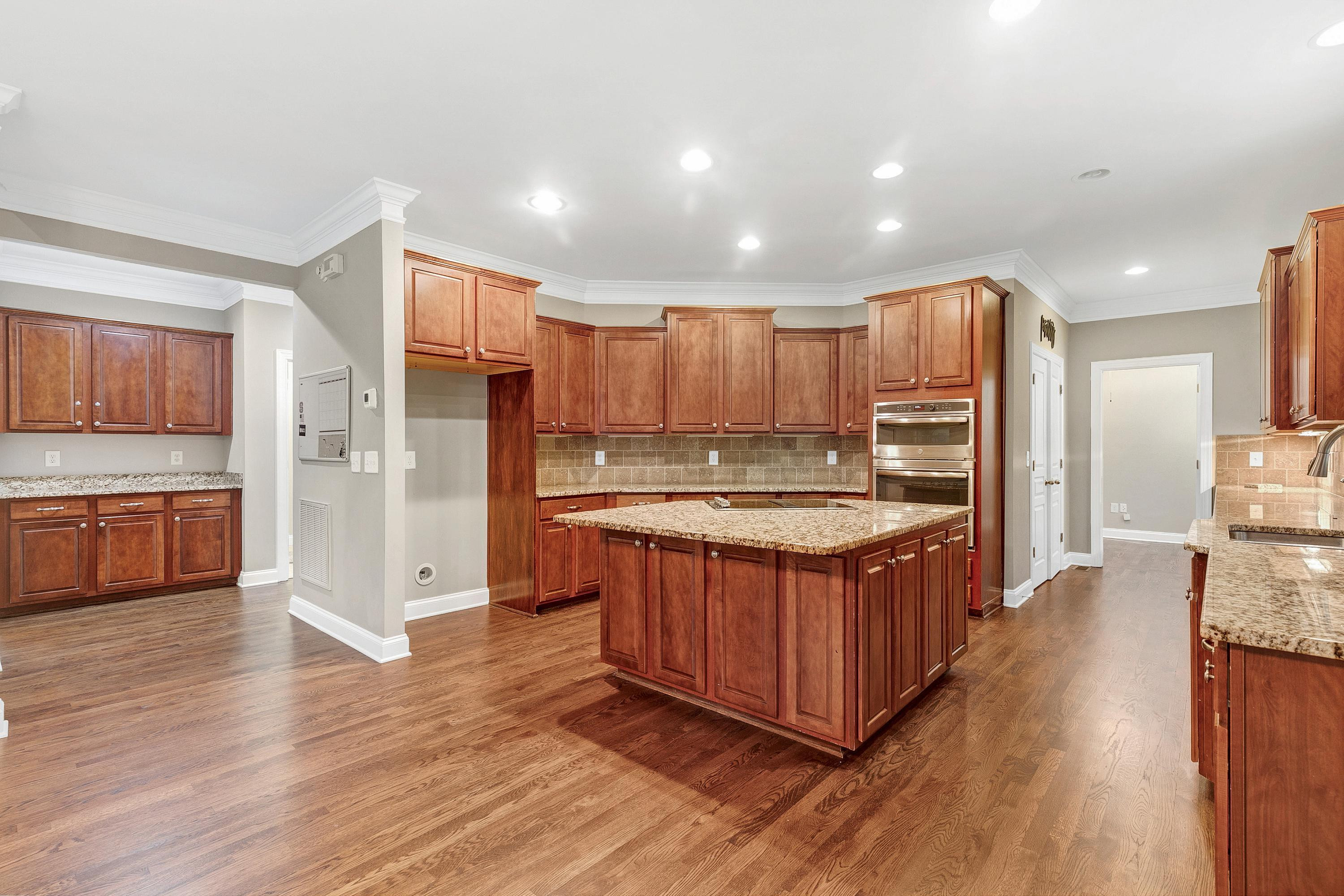 8431 Henderson Road Apex, NC 27539 - Photo 17 of 56 a kitchen with stainless steel appliances granite countertop a stove a refrigerator a sink a oven and wooden cabinets with wooden floor