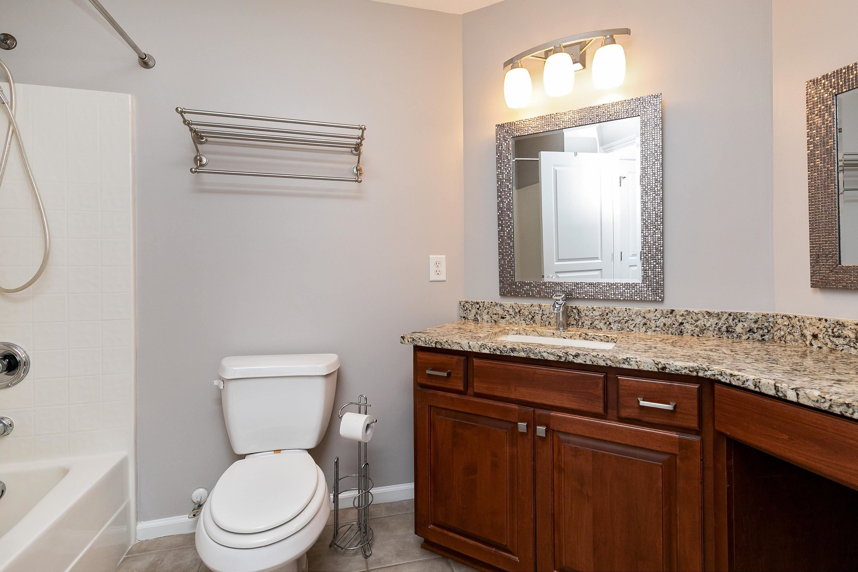 8431 Henderson Road Apex, NC 27539 - Photo 37 of 56 a bathroom with a granite countertop toilet sink and mirror