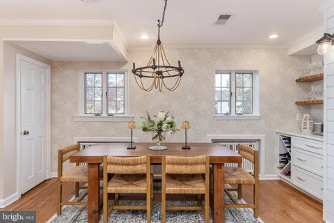 a kitchen with stainless steel appliances kitchen island granite countertop a refrigerator a sink a stove a dining table and chairs with wooden floor
