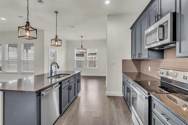 a kitchen with stainless steel appliances granite countertop a sink a stove and a wooden floors